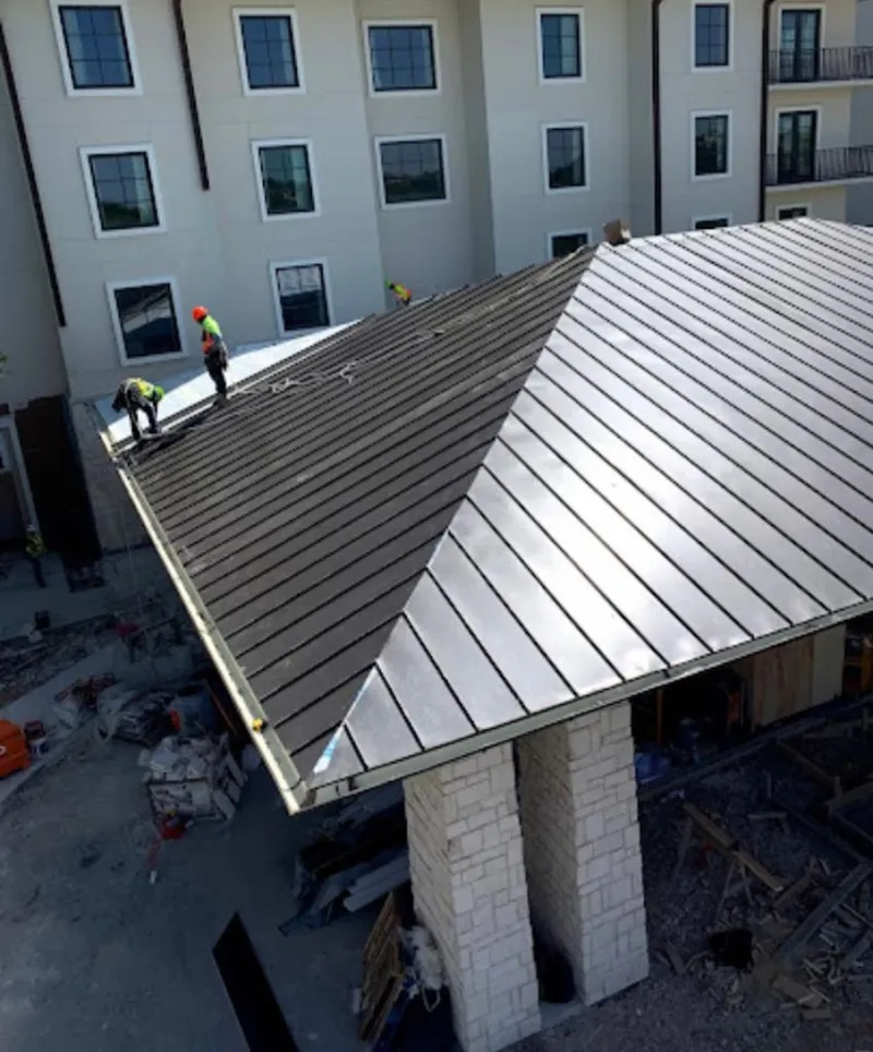 Crew installing standing seam metal roof panels on a commercial project in Rome
